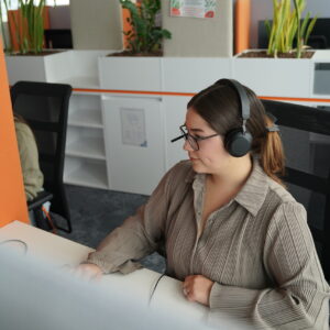 Eine Frau mit Headset vor einem Computerbildschirm