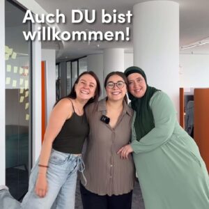 Drei Frauen stehen im Bild und umarmen sich, sie lachen in die Kamera und es steht