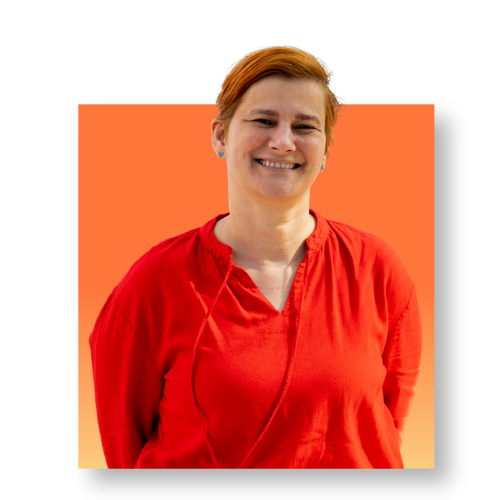 eine Frau im Portrait mit kurzen, orangenen Haaren und einem roten Shirt. vor einem quadratischen Hintergrund in Orange