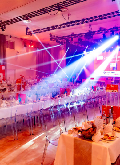 eine Eventhalle in rotem Licht und blauen Scheinwerrfern
