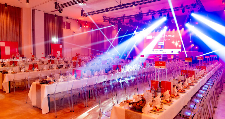 eine Eventhalle in rotem Licht und blauen Scheinwerrfern