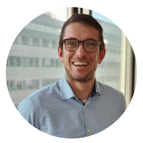 Ein Portrait von einem Mann mit großer Brille und kurzen Haaren. Er lacht.
